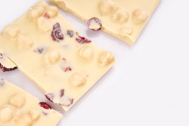 Çikolatalı çikolatanın makro fotoğrafı. Kırık parçalar beyaz arka planda. Beyaz arka planda fındıklı süt çikolataları.