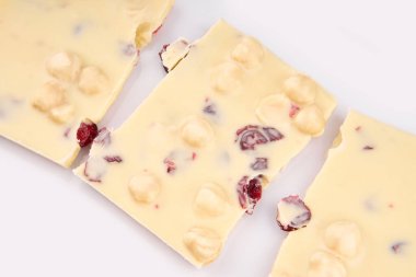 Çikolatalı çikolatanın makro fotoğrafı. Kırık parçalar beyaz arka planda. Beyaz arka planda fındıklı süt çikolataları.