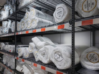 Dnipro, Ukrayna 10.12.2025: Yuvarlak ve plastik sarılı yorgan ve yorganlarla dolu bir mağazada depo tarzı raf ünitesi. Perakende, yatak, tekstil ve depo konseptleri için uygun