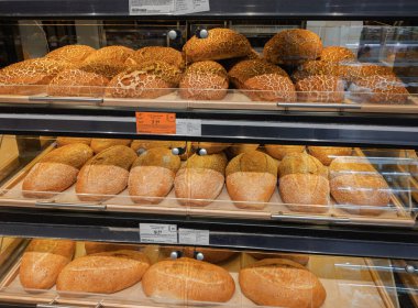 Dnipro, Ukrayna 10.13.2025: Bir bakkal veya fırın vitrinindeki raflarda görülebilir fiyat etiketleriyle sergilenen taze baget ve çeşitli somun ekmekler. Yemek ve perakende için ideal.