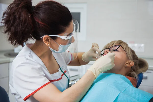 Closeup shot of dentist in protection mask working with tooth cavity.