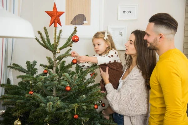 Beautiful family decorating Christmas tree together.