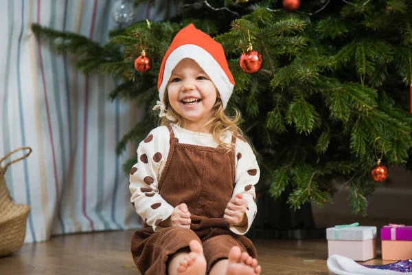 Cute little girl with disco ball sit on floor neat Christmas tree. Rechtenvrije Stockafbeeldingen