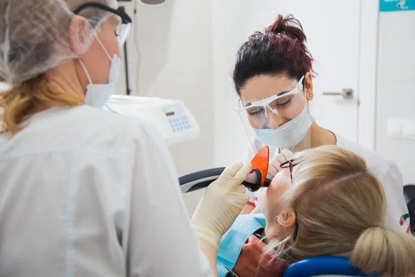 Closeup shot of dentist and assistant in protection mask working with tooth cavity.