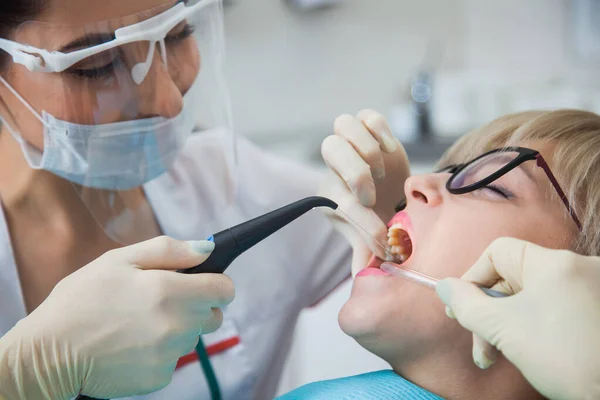 Стоматолог в защитной маске промывает рот от зубной пыли и крови Стоковая Картинка