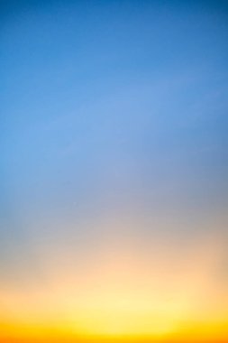 Sunset or sunrise sky with a vibrant gradient of orange, gold, and soft blue. Clear atmosphere with wispy clouds. Peaceful, natural light background. hope, freedom, new day Concepts, Vertical
