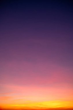 Sunset or sunrise sky with a vibrant gradient of orange, gold, and soft blue. Clear atmosphere with wispy clouds. Peaceful, natural light background. hope, freedom, new day Concepts, Vertical