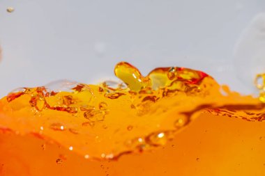 Canlı turuncu sıvı sıçraması, dinamik dalgalar ve damlacıklar yaratıyor. Yüksek hızlı soyut çekim içecek, meyve suyu, soda veya enerji içeceği reklamı ve içecek promosyonu için mükemmeldir.