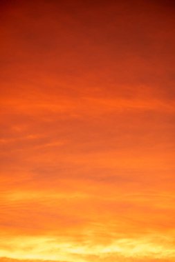 Sıcak turuncu ve mor bulutlu renkli günbatımı gökyüzü dramatik bir doğal arkaplan oluşturuyor. Doğa, seyahat, manzara ve soyut tasarım kullanımı için yumuşak akşam ışığı, güzel karanlık gökyüzü