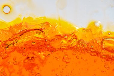 Canlı turuncu sıvı sıçraması, dinamik dalgalar ve damlacıklar yaratıyor. Yüksek hızlı soyut çekim içecek, meyve suyu, soda veya enerji içeceği reklamı ve içecek promosyonu için mükemmeldir.