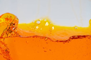 Canlı turuncu sıvı sıçraması, dinamik dalgalar ve damlacıklar yaratıyor. Yüksek hızlı soyut çekim içecek, meyve suyu, soda veya enerji içeceği reklamı ve içecek promosyonu için mükemmeldir.