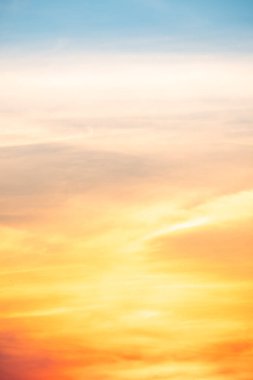 Sunset or sunrise sky with a vibrant gradient of orange, gold, and soft blue. Clear atmosphere with wispy clouds. Peaceful, natural light background. hope, freedom, new day Concepts, Vertical