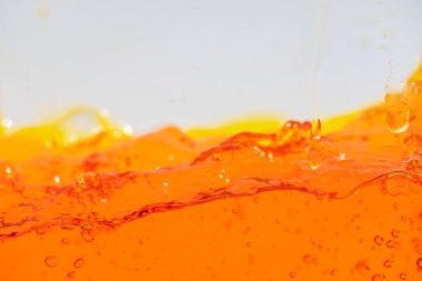 Canlı turuncu sıvı sıçraması, dinamik dalgalar ve damlacıklar yaratıyor. Yüksek hızlı soyut çekim içecek, meyve suyu, soda veya enerji içeceği reklamı ve içecek promosyonu için mükemmeldir.