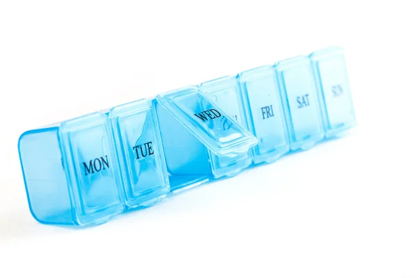 Mavi plastik organizatör, beyaz arka planda izole edilmiş haplar için. Kompartıman haplarının kapakçığı tıpla yakın plan görüntüsü. Günlük vitaminler ve takviyeler rutin dozaj konsepti.