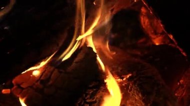 Ateşin içinde odun yanıyor. Şöminedeki ateş sönüyor. Kapatın. Kırmızı-turuncu kömürler karanlıkta yanıp sönüyor. Ahşap yüksek sıcaklıktan çatlıyor.