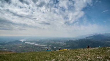 Paragliderler sırayla dağdan havalanır. Zaman ayarlı. Kanatlarını dağ yamacına açıp uçarlar. Güzel bulutlar gökyüzünde süzülür