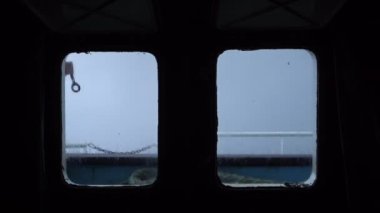 Kamara penceresinden fırtına manzarası. Güçlü bir atış. Geminin penceresinden deniz manzarası. Dalgalar yana çarpar ve gökyüzünü kaplar. Çok güçlü bir fırtına. Köpüklü yüksek dalgalar pencerelerden görülebilir..