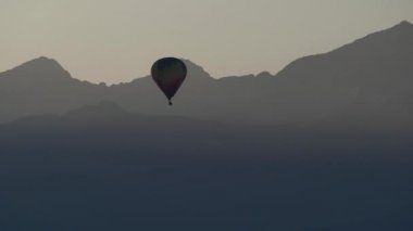 Balon yükseliyor. Dağlar çizgisi. Çok renkli bir top. Sis içindeki dağlar. Gökyüzünde sabah sisi