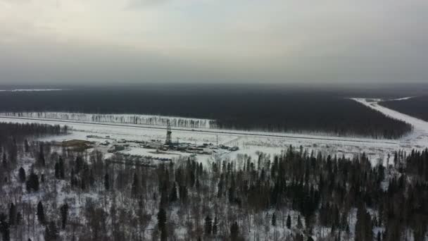 Нефтяная вышка зимой в лесу. Вид с воздуха. Тучные, серые леса вокруг — стоковое видео