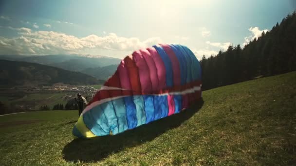 Paraglider stijgt op vanaf een heuvel. Hij rent omhoog, steekt zijn vleugel op en stijgt op van de grond.. — Stockvideo