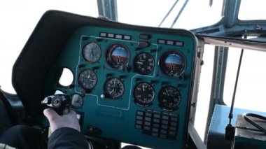 Helikopter kokpiti ve pilotlar direksiyonda el ele tutuşuyorlar. Mi-8 helikopterinin kabini. Helikopter uçuyor. Enstrümanlı yeşil panel