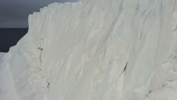 Snow Rock na costa. Iceberg no mar. Pedras negras na neve. A câmara sobe. Mar e montanhas na neve atrás. Vista do helicóptero — Vídeo de Stock