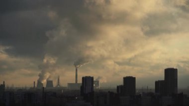 Smoke from pipes above city. Smoke rises to sky over high residential buildings. Thermal power plant near the town. Air pollution.