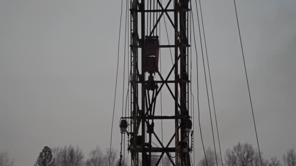 Equipamento de perfuração. Drill gira Top drive vai para baixo. Torre de metal. Suportes amarelos. Suportes metálicos contra o céu. O guindaste levanta uma tubulação metálica — Vídeo de Stock