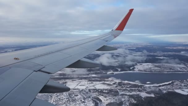 비행기 날개. 조명 장치에서 바라봐. 구름은 아래쪽으로 날아들어 옵니다. 겨울. 라일락, 푸른 눈. 아름다운 풍경이야. 강, 숲, 마을 — 비디오