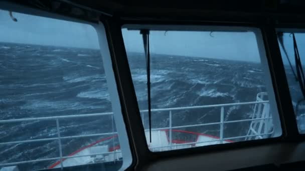 Nave en tormenta. Vista desde el puente. El barco sube a la ola. Muchas salpicaduras en las ventanas. Lanzamiento fuerte. Las olas altas golpean la nave. Espuma blanca sobre agua. — Vídeos de Stock