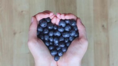 Bir çocuğun eli, kadının elinde yatan yaban mersinine uzanır..