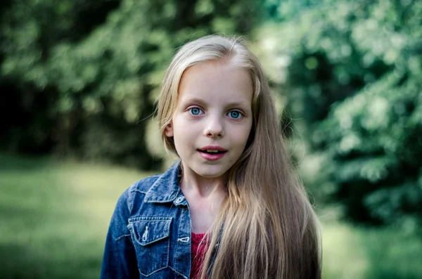 Verbaasd schattig klein blond meisje bij zomer veld. — Stockfoto