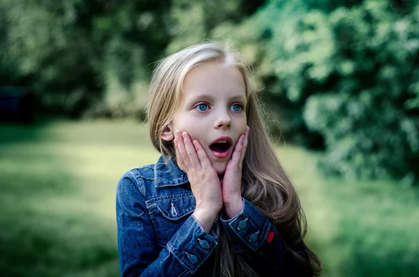Verbaasd schattig klein blond meisje bij zomer veld. — Stockfoto