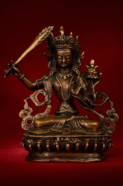 Statueta lui Manjushri răsucind sabia înțelepciunii pe un spate roșu — Fotografie, imagine de stoc