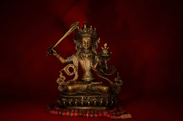 Statueta lui Manjushri răsucind sabia înțelepciunii pe un spate roșu — Fotografie, imagine de stoc