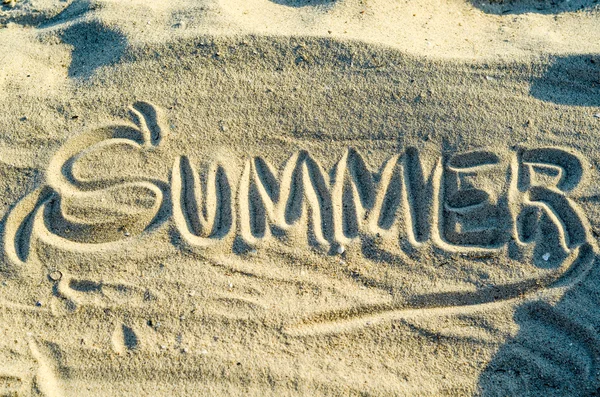 Ordet "sommer" er håndskrevet på sanden. . – stockfoto