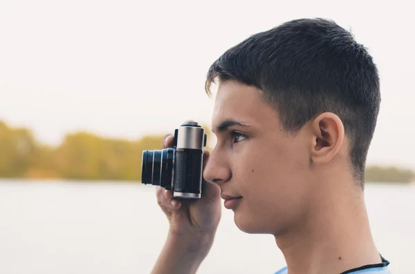 Leuke jongen tiener met vintage meetzoeker camera. — Stockfoto