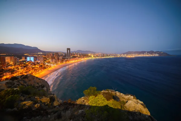 มุมมองของชายฝั่งใน Benidorm ที่พระอาทิตย์ตกด้วยแสงไฟในเมือง — ภาพถ่ายสต็อก