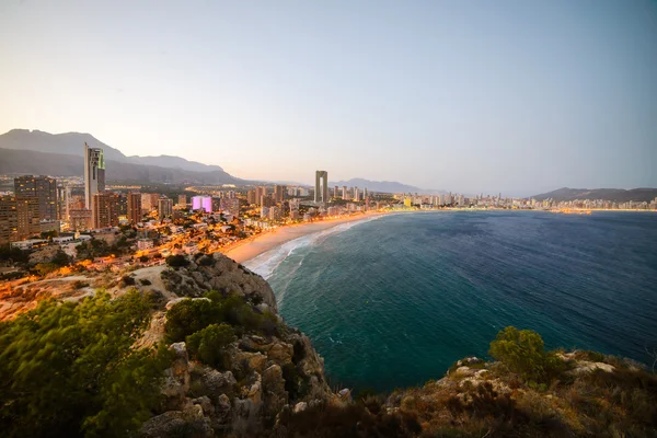 มุมมองของชายฝั่งใน Benidorm ที่พระอาทิตย์ตกด้วยแสงไฟในเมือง — ภาพถ่ายสต็อก