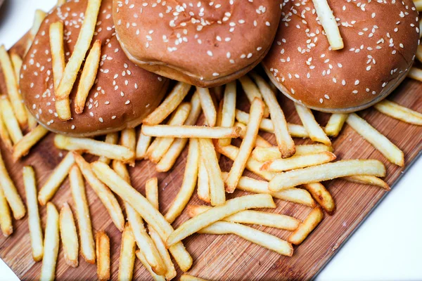 Burger buns with french fries on wooden background — Stock Photo, Image