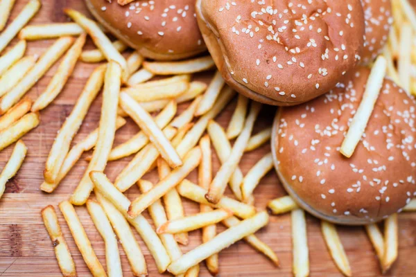 Burger buns with french fries on wooden background — Stock Photo, Image