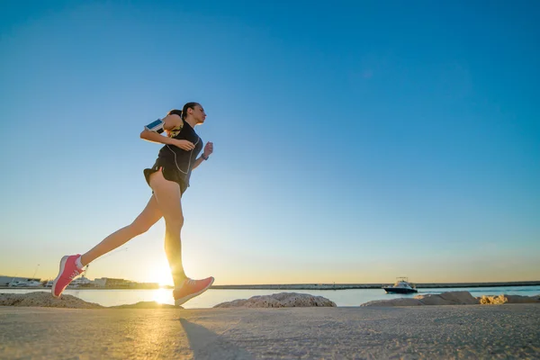 Joven chica deportiva corriendo sola en la hermosa puesta de sol en la playa — Foto de Stock