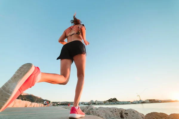 Joven chica deportiva corriendo sola en la hermosa puesta de sol en la playa — Foto de Stock