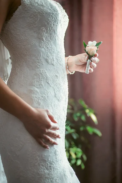 Brud holding bröllop boutonniere i händerna — Stockfoto