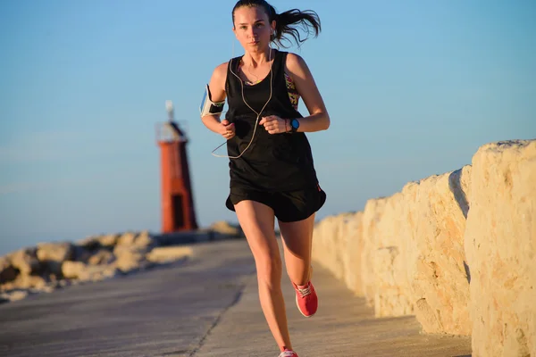 Joven chica deportiva corriendo sola en el hermoso atardecer cerca de la tapa — Foto de Stock