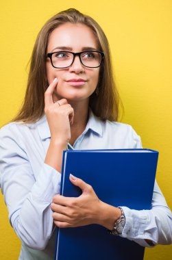 Gülümseyen bir şey hakkında düşünüyor ve klasör tutarak akıllı güzel kadın