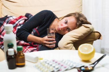 Yün battaniyenin altında kanepede yatan hasta kadın