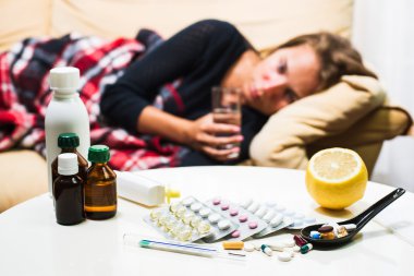 Yün battaniyenin altında kanepede yatan hasta kadın