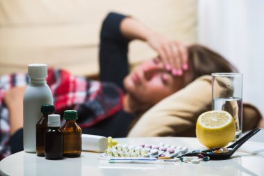 Yün battaniyenin altında kanepede yatan hasta kadın