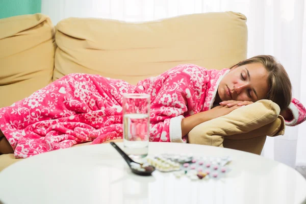 Femme malade couchée dans son lit en robe de chambre en regardant thermomètre et pilules — Photo